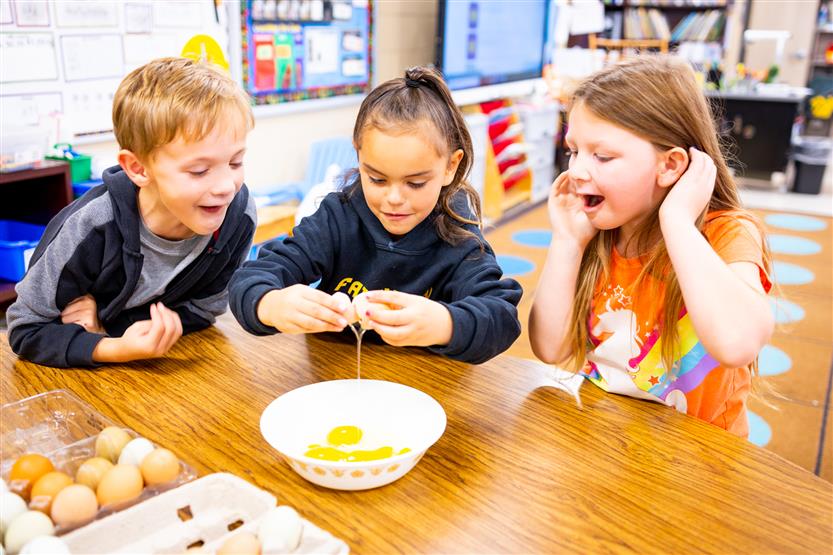Students crack an egg into a bowl